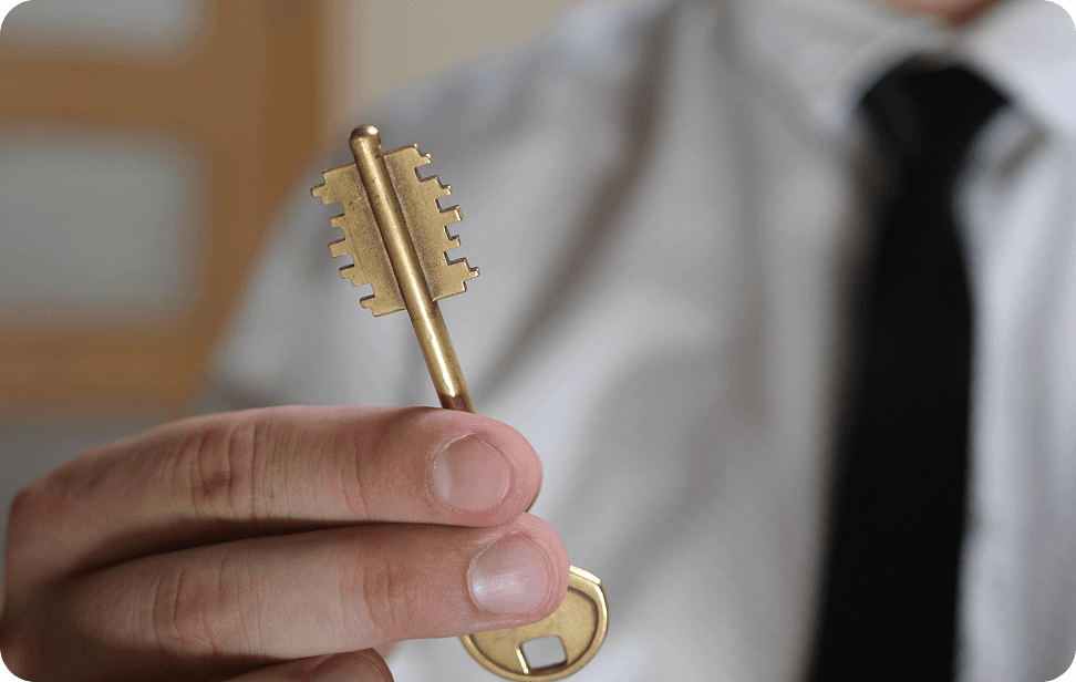 A man dressed in a shirt and tie is holding a shiny golden key, representing a significant achievement.